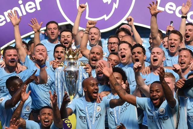Manchester City's Spanish manager Pep Guardiola (C) holds the Premier League trophy on the pitch with Manchester City players after the English Premier League football match between Manchester City and Huddersfield Town at the Etihad Stadium in Manchester, north west England, on May 6, 2018. Manchester City have been found guilty of all but one of 115 Premier League charges they face for breaching financial regulations, the Athletic reported on Friday, September 25, 2026. (Photo by Oli SCARFF / AFP)
