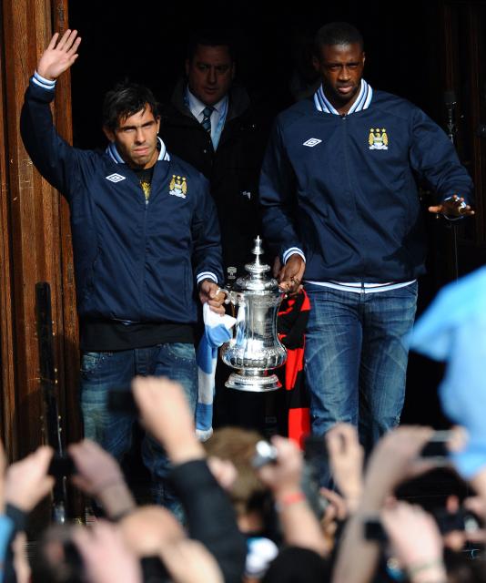 (FILES) Manchester City's Argentinian forward Carlos Tevez (L) and Manchester City's Ivorian defender Yaya Toure (R) leave Manchester Town Hall carrying the FA Cup in Manchester, north west England, on May 23, 2011 for an open top bus tour of the city. Manchester City footbal club won their first trophy in 35 years by beating Stoke City 1-0 at Wembley Stadium. Manchester City have been found guilty of all but one of 115 Premier League charges they face for breaching financial regulations, the Athletic reported on Friday, September 25, 2026. (Photo by Paul ELLIS / AFP)