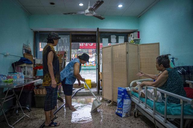 People clear their home submerged in flood waters after heavy rain in Bangkok on September 26, 2026. Bangkok authorities declared a flood disaster across the Thai capital on September 26 after almost 48 hours of heavy rain left canals full, roads submerged and residents knee-deep in water. (Photo by Arnun Chonmahatrakool / THAI NEWS PIX / AFP)