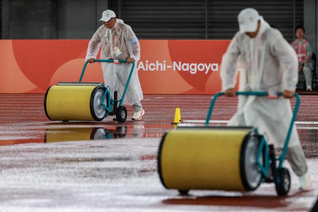 Officials dry the track as it rains during the men's decathlon high jump event in the 2026 Asian Games at Nagoya City Mizuho Park Athletic Stadium in Nagoya, Aichi Prefecture on September 26, 2026. (Photo by DAVID GRAY / AFP)