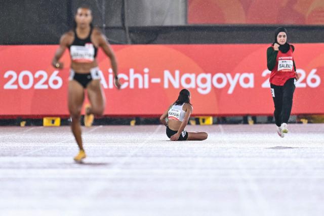 Uzbekistan's Jonbibi Hukmova (C) falls on the track as Afghanistan's Marwa Saleem (R) and Lebanon's Aziza Sbaity compete during the women's 200m heat in the 2026 Asian Games at Nagoya City Mizuho Park Athletic Stadium in Nagoya, Aichi Prefecture on September 26, 2026. (Photo by MOHD RASFAN / AFP)
