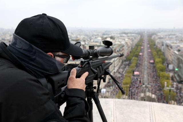 A sniper of French Police Brigade d'Intervention (BI) of Paris unit looks through the sight of his rifle ontop of the Arc de Triomphe monument as the crowd gather on the Champs-Elysees avenue to attend the Pope's solemn outdoor mass at Place de la Concorde in central Paris, on September 26, 2026 on the second day of his visit to France. (Photo by Sameer AL-DOUMY / AFP)