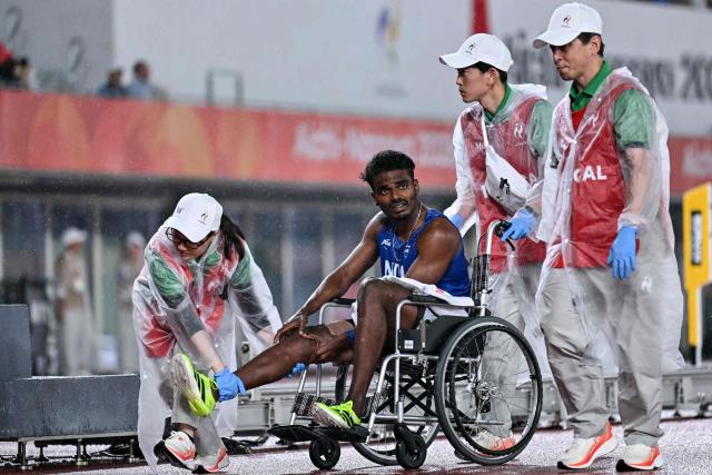 India's Thowfeeq Noushad is being carried on wheelchair after an injury in the men's decathlon 400 metres heat during the 2026 Asian Games at Nagoya City Mizuho Park Athletic Stadium in Nagoya, Aichi Prefecture on September 26, 2026. (Photo by MOHD RASFAN / AFP)