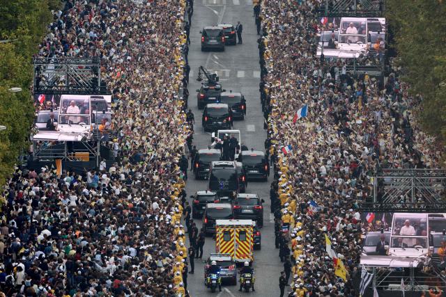 A photograph taken from the roof of the Arc de Triomphe shows Pope Leo XIV waving to the crowd from the Papamobile (popemobile) as he rides down the Champs-Elysees Avenue to arrive at Place de la Concorde, central Paris, on September 26, 2026 to celebrate a solemn outdoor mass on the second day of his visit to France. Pope Leo XIV celebrates an open-air mass for hundreds of thousands of believers on the Champs Elysees in Paris, after saying it was possible to "live together in dignity and peace". (Photo by Sameer AL-DOUMY / AFP)