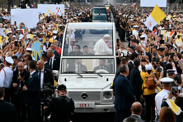 Pope Leo XIV touches the head of a child as he rides down the Champs-Elysees Avenue in the Papamobile (popemobile) on his way to the Place de la Concorde, central Paris, on September 26, 2026, to celebrate a solemn outdoor mass, on the second day of his visit to France. Pope Leo XIV celebrates an open-air mass for hundreds of thousands of believers on the Champs Elysees in Paris, after saying it was possible to "live together in dignity and peace". (Photo by Alberto PIZZOLI / AFP)