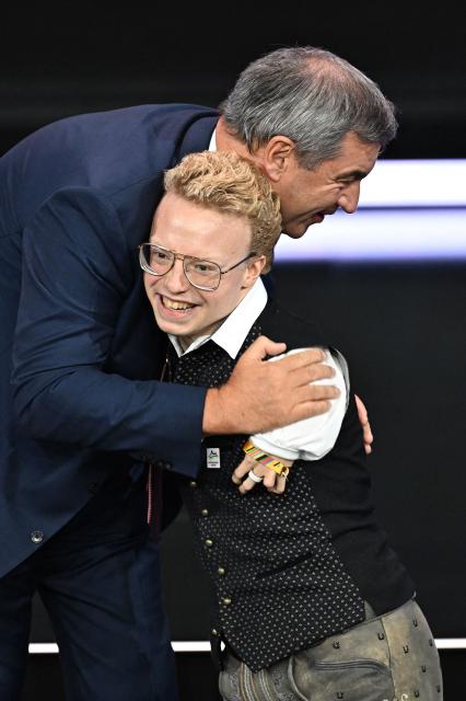 Bavaria's State Premier Markus Soeder and German Paralympic swimmer Josia Topf react on stage at the Kurhaus in Baden-Baden, southwestern Germany, on September 26, 2026, during the German Olympic Sports Confederation's (DOSB) announcement of its national bid to host the Olympic Games in Germany. (Photo by Uwe ANSPACH / AFP)