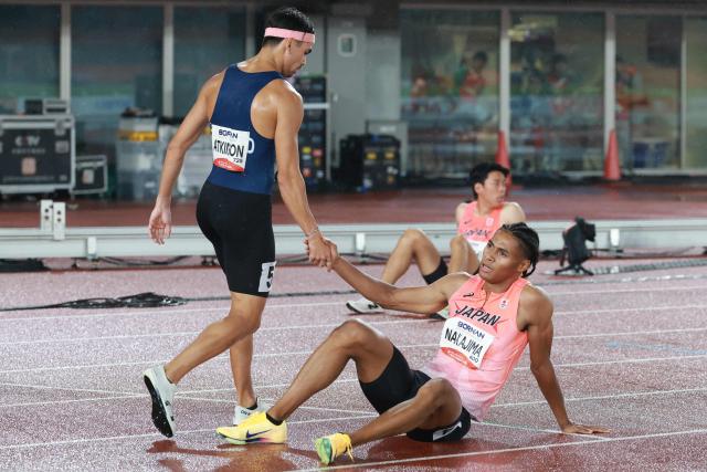 Gold medalist Thailand's Joshua Atkinson (L) shakes hands with bronze medalist Japan's Yuki Joseph Nakajima after the men's 400m final during the 2026 Asian Games at Nagoya City Mizuho Park Athletic Stadium in Nagoya, Aichi Prefecture on September 26, 2026. (Photo by DAVID GRAY / AFP)