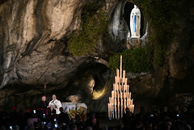 Pope Leo XIV leads a prayer with worshippers near Italian Archbishop Diego Ravelli (L) at the Grotto of Massabielle in the Sanctuary of Our Lady of Lourdes, southwestern France, on September 26, 2026 on the second day of his visit to France. (Photo by Lionel BONAVENTURE / AFP)