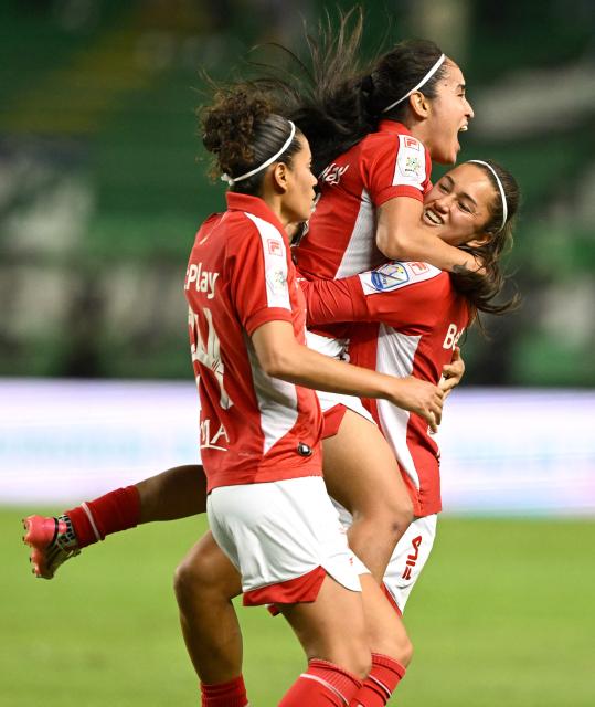 Santa Fe forward #07 Mariana Zamorano (top) celebrates with teammates after scoring the opening goal during the Colombian women's football league second leg final match between Deportivo Cali and Independiente Santa Fe at the Deportivo Cali Stadium in Cali, Colombia on September 26, 2026. (Photo by JOAQUIN SARMIENTO / AFP)