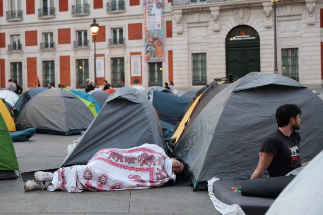 A person sleep outside a tent as demonstrators camp one day after a protest against evictions and the housing crisis in front of the Presidency of the Community of Madrid on the Puerta del Sol plaza in Madrid on September 27, 2026. Spain's main tenants' unions on September 25 urged the government to pass a new law to tackle the country's housing crisis after an 87-year-old was evicted from her Madrid home, sparking nationwide protests. (Photo by Thomas COEX / AFP)