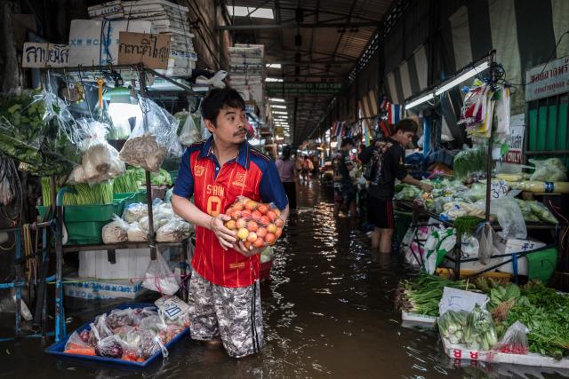 A vendor sells vegetables from a stall surrounded by flood waters in the Bang Kapi district of Bangkok on September 27, 2026. Thousands of Bangkok residents awoke in shelters on September 27 after flooding triggered by days of heavy rain in the Thai capital inundated homes and roads, with some starting to dry out their homes and belongings. (Photo by Chanakarn LAOSARAKHAM / AFP)