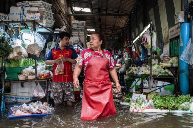 Vendors selling vegetables look next to stalls surrounded by flood waters in the Bang Kapi district of Bangkok on September 27, 2026. Thousands of Bangkok residents awoke in shelters on September 27 after flooding triggered by days of heavy rain in the Thai capital inundated homes and roads, with some starting to dry out their homes and belongings. (Photo by Chanakarn LAOSARAKHAM / AFP)