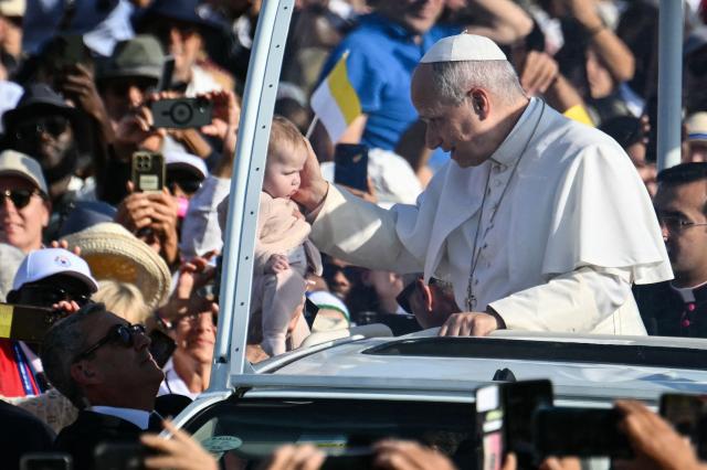 TOPSHOT - Pope Leo XIV blesses a child as he arrives on board of the Papamobile (popemobile) to celebrate a holy mass at the Prairie of the Shrine of Our Lady of Lourdes, southwestern France, on September 27, 2026 on the third day of his visit to France. (Photo by Alberto PIZZOLI / AFP)