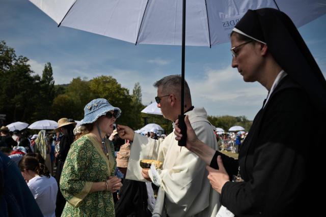 A priest distributes the communion to a worshipper during the holy mass celebrated by Pope Leo XIV at the Prairie of the Shrine of Our Lady of Lourdes, southwestern France, on September 27, 2026 on the third day of his visit to France. (Photo by Ed JONES / AFP)