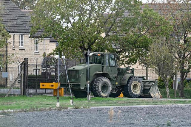 Heavy machinery (C) is pictured blocking off an entrance to RAF Fairford base, in Fairford, south-west England on September 27, 2026, as UK counter-terrorism police investigate an incident near the base in the village of Whelford. British police on September 27 declared a major incident and evacuated villagers living near a base used by the US air force after arresting several men on suspicion of explosives offences. (Photo by JUSTIN TALLIS / AFP)