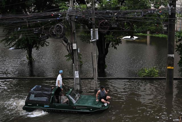 People wade through floodwaters in Bang Kapi district, Bangkok on September 27, 2026. Deep floodwaters in Bangkok drove thousands of residents into shelters as others scrambled to buy groceries or dry out their homes on September 27, after days of heavy rain inundated markets, roads and residences. (Photo by Lillian SUWANRUMPHA / AFP)
