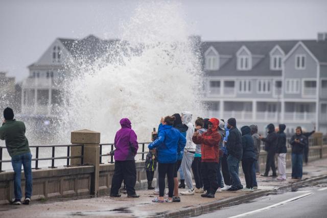 Onlookers watch waves crash onto the shore during a noreaster storm in Hampton, New Hampshire, on September 27, 2026. A powerful autumnal storm lashed the heavily populated US Northeast corridor with wind, rain and large waves, knocking out power for thousands and killing at least one person. Nor'easters, as storms like these are known, can cause billions of dollars in damage as they bring torrential rain, sometimes snow, strong winds and heavy storm surge flooding to large swaths of the US East Coast. The National Weather Service (NWS) said Sunday morning that the storm was "slowly weakening" after causing days of havoc up and down the East Coast. (Photo by Joseph Prezioso / AFP)