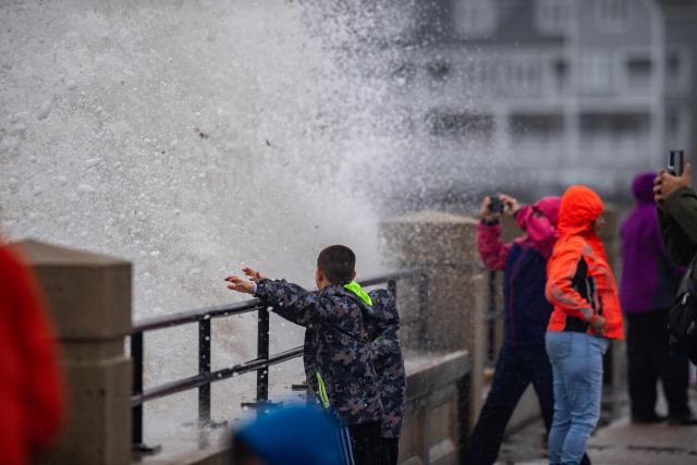 Onlookers watch waves crash onto the shore during a noreaster storm in Hampton, New Hampshire, on September 27, 2026. A powerful autumnal storm lashed the heavily populated US Northeast corridor with wind, rain and large waves, knocking out power for thousands and killing at least one person. Nor'easters, as storms like these are known, can cause billions of dollars in damage as they bring torrential rain, sometimes snow, strong winds and heavy storm surge flooding to large swaths of the US East Coast. The National Weather Service (NWS) said Sunday morning that the storm was "slowly weakening" after causing days of havoc up and down the East Coast. (Photo by Joseph Prezioso / AFP)