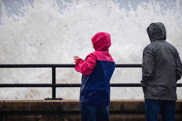 Onlookers watch waves crash onto the shore during a noreaster storm in Hampton, New Hampshire, on September 27, 2026. A powerful autumnal storm lashed the heavily populated US Northeast corridor with wind, rain and large waves, knocking out power for thousands and killing at least one person. Nor'easters, as storms like these are known, can cause billions of dollars in damage as they bring torrential rain, sometimes snow, strong winds and heavy storm surge flooding to large swaths of the US East Coast. The National Weather Service (NWS) said Sunday morning that the storm was "slowly weakening" after causing days of havoc up and down the East Coast. (Photo by Joseph Prezioso / AFP)