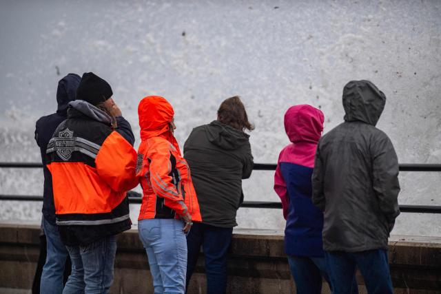 Onlookers watch waves crash onto the shore during a noreaster storm in Hampton, New Hampshire, on September 27, 2026. A powerful autumnal storm lashed the heavily populated US Northeast corridor with wind, rain and large waves, knocking out power for thousands and killing at least one person. Nor'easters, as storms like these are known, can cause billions of dollars in damage as they bring torrential rain, sometimes snow, strong winds and heavy storm surge flooding to large swaths of the US East Coast. The National Weather Service (NWS) said Sunday morning that the storm was "slowly weakening" after causing days of havoc up and down the East Coast. (Photo by Joseph Prezioso / AFP)
