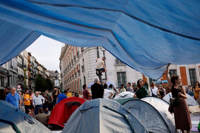 Demonstrators camp with tents to protest against evictions and the housing crisis in front of the Presidency of the Community of Madrid on the Puerta del Sol plaza in Madrid on September 27, 2026. Signs read 'Vulture funds out you go' and 'Evict a pensioner is shameful'. Spain's main tenants' unions on September 25 urged the government to pass a new law to tackle the country's housing crisis after an 87-year-old was evicted from her Madrid home, sparking nationwide protests. (Photo by Oscar DEL POZO / AFP)