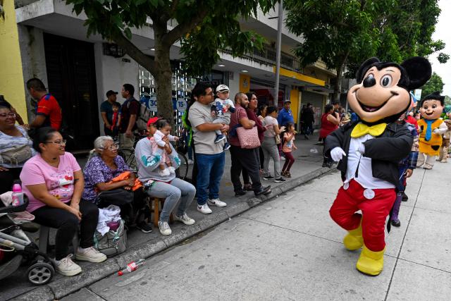 A dancer wearing a costume of the Disney character Mickey Mouse performs during a "Convite," a traditional dance festival in Guatemala City on September 27, 2026. (Photo by Johan ORDONEZ / AFP)