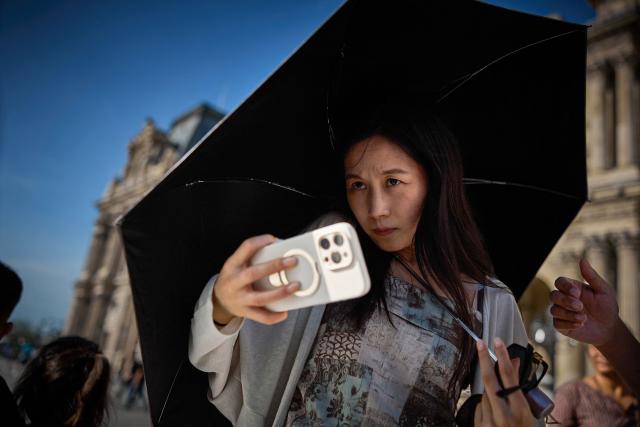 A visitor takes a photograph in the Napoleon courtyard of the Louvre Museum on World Tourism Day in Paris on September 27, 2026. The Louvre remained the world’s most visited museum in 2025, welcoming more than nine million visitors. (Photo by Kiran RIDLEY / AFP)