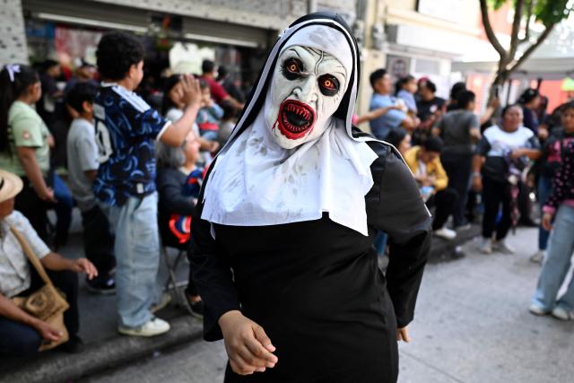 A dancer wearing a costume of the movie character The Nun performs during a "Convite," a traditional dance festival in Guatemala City on September 27, 2026. (Photo by Johan ORDONEZ / AFP)