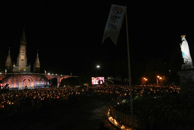 Faithfuls watch the Rosary Prayer on a giant screen in the forecourt of the Basilica of the Holy Rosary before a torchlight procession with Pope Leo XIV in Lourdes southwestern France, on September 27, 2026 on the third day of his trip to France. (Photo by Lionel BONAVENTURE / AFP)