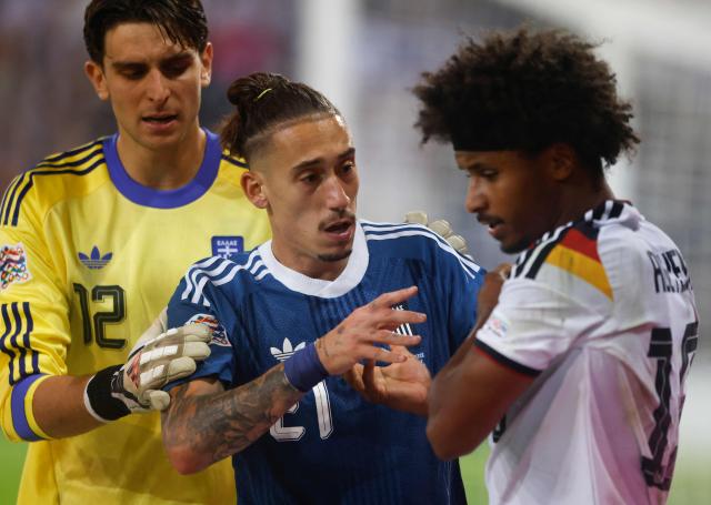 (L-R) Greece's goalkeeper #12 Kostas Tzolakis, Greece's defender #21 Konstantinos Tsimikas and Germany's midfielder #19 Karim Adeyemi discuss during the UEFA Nations League Group A2 between Germany and Greece in Augsburg, southern Germany on September 27, 2026. (Photo by Michaela STACHE / AFP)