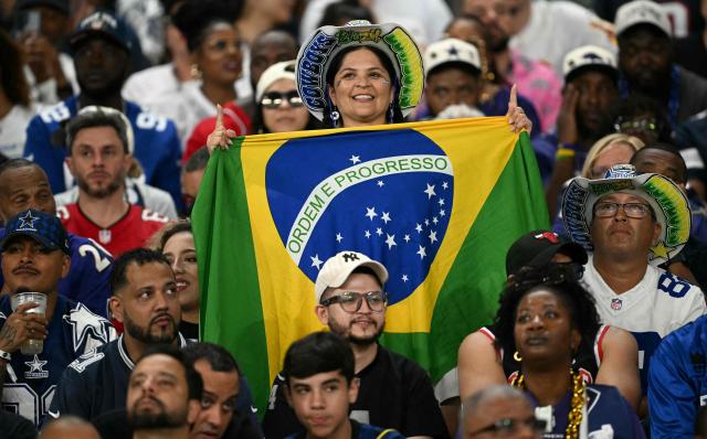 A Cowboys fan holds a Brazilian flag during the NFL match between the Dallas Cowboys and the Baltimore Ravens at the Maracana Stadium in Rio de Janeiro, Brazil, on September 27, 2026. (Photo by MAURO PIMENTEL / AFP)