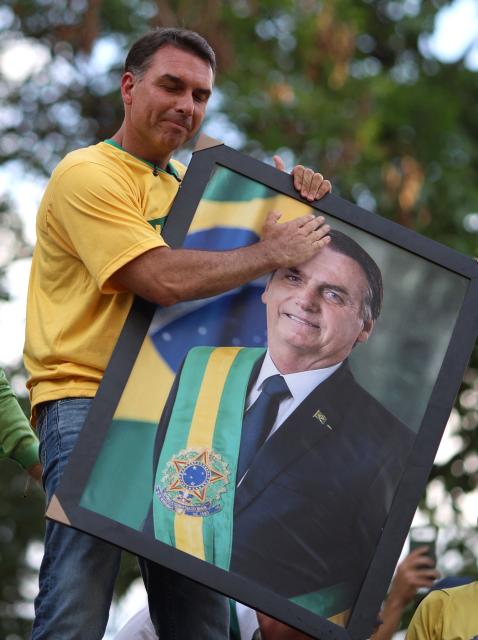 Brazilian right-wing presidential candidate Flavio Bolsonaro holds a picture of his father, convicted former President Jair Bolsonaro, during a motorcade with supporters in Goiania, Brazil, on September 27, 2026. Brazil will hold presidential election on October 4, 2026. (Photo by Sergio Lima / AFP)