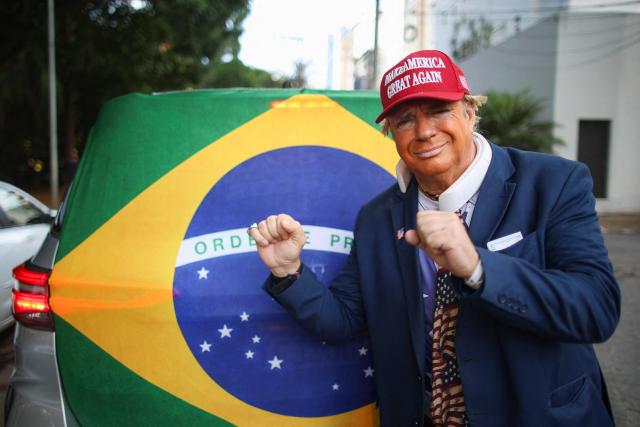 A man wearing a mask depicting US President Donald trump attends a rally of Brazilian right-wing presidential candidate Flavio Bolsonaro in Goiania, Brazil, on September 27, 2026. Brazil will hold presidential election on October 4, 2026. (Photo by Sergio Lima / AFP)