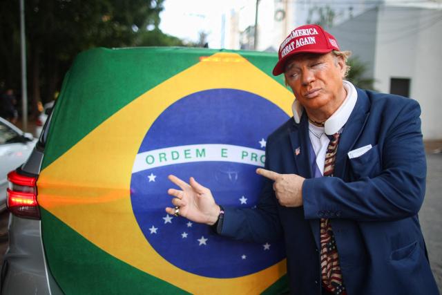 A man wearing a mask depicting US President Donald trump attends a rally of Brazilian right-wing presidential candidate Flavio Bolsonaro in Goiania, Brazil, on September 27, 2026. Brazil will hold presidential election on October 4, 2026. (Photo by Sergio Lima / AFP)