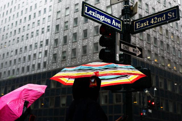 People walk in the rain near Grand Central terminal in New York on September 27, 2026. A powerful off-season storm kept lashing the heavily populated US Northeast corridor on Sunday with wind, rain and large waves, knocking out power for thousands and killing at least one person. (Photo by CHARLY TRIBALLEAU / AFP)