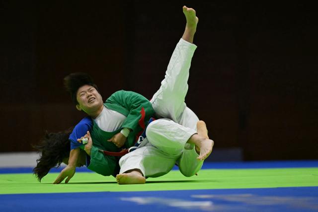 Mongolia's Naidansuren Byambasuren (in blue) and South Korea's Mo Su-min (in green) compete in the women's under 78kg quarter-final kurash event in the 2026 Asian Games at the Aichi Prefectural Martial Arts Hall in Nagoya on September 28, 2026. (Photo by MOHD RASFAN / AFP)