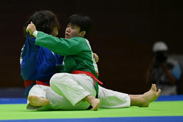 Mongolia's Naidansuren Byambasuren (in blue) and South Korea's Mo Su-min (in green) compete in the women's under 78kg quarter-final kurash event in the 2026 Asian Games at the Aichi Prefectural Martial Arts Hall in Nagoya on September 28, 2026. (Photo by MOHD RASFAN / AFP)