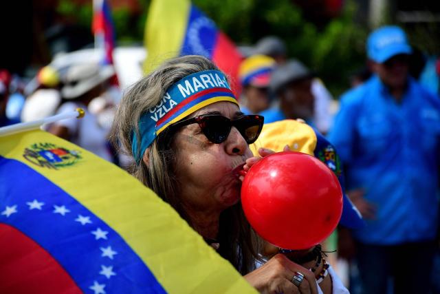 A demonstrator inflates a red balloon during a rally to demand the return of opposition leader Maria Corina Machado to the country on a street in Valencia, Carabobo Sate on Sepetember 27, 2026. Supporters of Machado mobilized in caravans across several regions on September 27, 2026, to demand her "safe return" to the country. (Photo by Jacinto OLIVEROS / AFP)