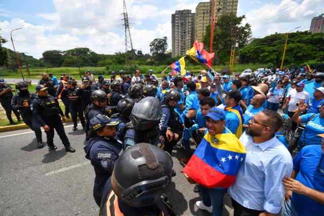 Demonstrators argue with police officers during a rally to demand the return of opposition leader Maria Corina Machado to the country on a street in Valencia, Carabobo Sate on Sepetember 27, 2026. Supporters of Machado mobilized in caravans across several regions on September 27, 2026, to demand her "safe return" to the country. (Photo by Jacinto OLIVEROS / AFP)