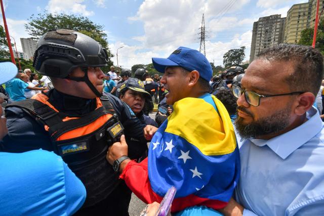 A demonstrator argues with police officers during a rally to demand the return of opposition leader Maria Corina Machado to the country on a street in Valencia, Carabobo Sate on Sepetember 27, 2026. Supporters of Machado mobilized in caravans across several regions on September 27, 2026, to demand her "safe return" to the country. (Photo by Jacinto OLIVEROS / AFP)