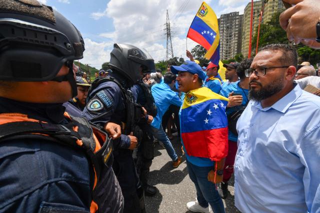 A demonstrator argues with police officers during a rally to demand the return of opposition leader Maria Corina Machado to the country on a street in Valencia, Carabobo Sate on Sepetember 27, 2026. Supporters of Machado mobilized in caravans across several regions on September 27, 2026, to demand her "safe return" to the country. (Photo by Jacinto OLIVEROS / AFP)