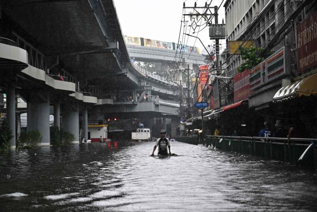 Residents navigate floodwaters and heavy rain in Bang Kapi district in Bangkok on September 28, 2026. Eight people have died in flooding in Thailand since September 16, although none in the capital Bangkok which declared a disaster this weekend following heavy rains, the government said on September 28. (Photo by Lillian SUWANRUMPHA / AFP)