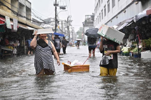 Residents navigate floodwaters and heavy rain in Bang Kapi district in Bangkok on September 28, 2026. Eight people have died in flooding in Thailand since September 16, although none in the capital Bangkok which declared a disaster this weekend following heavy rains, the government said on September 28. (Photo by Lillian SUWANRUMPHA / AFP)
