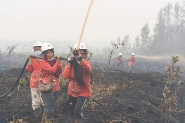Members of the all-women The Power of Mama (TPoM) volunteer firefighting team spray water onto smouldering peatland in Mensubuk Lama, Tanjungpura Village, Ketapang Regency, West Kalimantan on September 26, 2026. Indonesia has been battling fires for weeks in parts of Borneo and Sumatra, sending suffocating haze across the islands and neighbouring Malaysia and Singapore. (Photo by HERIBERTUS / AFP)