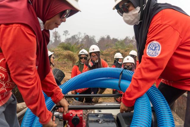 Members of the all-women The Power of Mama (TPoM) volunteer firefighting team set up a suction hose and other equipment to draw water from a nearby river as they battle smouldering peatland in Benipis, Ketapang Regency, West Kalimantan on September 26, 2026. Indonesia has been battling fires for weeks in parts of Borneo and Sumatra, sending suffocating haze across the islands and neighbouring Malaysia and Singapore. (Photo by HERIBERTUS / AFP)