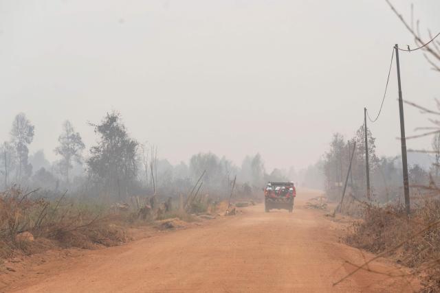 Members of the all-women The Power of Mama (TPoM) volunteer firefighting team ride on the flatbed of a truck along a dirt road toward the Benipis area in between Tanjungpura and Ulak Medang villages in Ketapang Regency, West Kalimantan on September 26, 2026. Indonesia has been battling fires for weeks in parts of Borneo and Sumatra, sending suffocating haze across the islands and neighbouring Malaysia and Singapore. (Photo by HERIBERTUS / AFP)