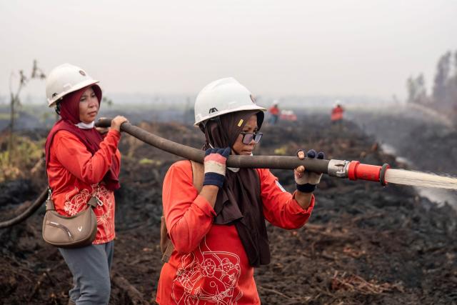 Members of the all-women The Power of Mama (TPoM) volunteer firefighting team spray water onto smouldering peatland in Mensubuk Lama, Tanjungpura Village, Ketapang Regency, West Kalimantan on September 26, 2026. Indonesia has been battling fires for weeks in parts of Borneo and Sumatra, sending suffocating haze across the islands and neighbouring Malaysia and Singapore. (Photo by HERIBERTUS / AFP)