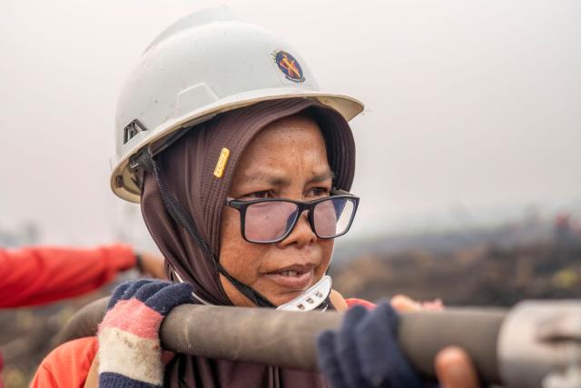 A member of the all-women The Power of Mama (TPoM) volunteer firefighting team sprays water onto smouldering peatland in Mensubuk Lama, Tanjungpura Village, Ketapang Regency, West Kalimantan on September 26, 2026. Indonesia has been battling fires for weeks in parts of Borneo and Sumatra, sending suffocating haze across the islands and neighbouring Malaysia and Singapore. (Photo by HERIBERTUS / AFP)