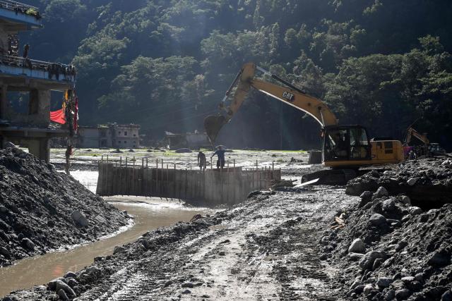 Workers use an excavator to remove sludge and debris from a blocked road in the aftermath of the August 26 flash flood, at Betrawati Bazaar in Nepal's Rasuwa district on September 28, 2026. The Himalayan nation suffered one of the worst catastrophes in its history late last month when a tsunami-like flood, triggered by a high-altitude glacial mountain collapse along the Nepal-China border, cut a swathe of destruction claiming more than 1,400 lives and leaving 5,000 unaccounted for. (Photo by PRAKASH MATHEMA / AFP)