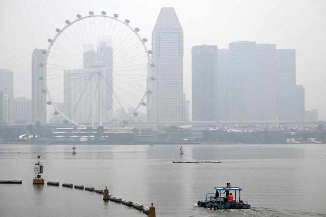 Workers sail along the Marina bay reservoir as the city skyline is shrouded with haze in Singapore on September 28, 2026. Indonesia has been battling fires for weeks in parts of Borneo and Sumatra, sending suffocating haze across the islands and neighbouring Malaysia and Singapore. (Photo by Roslan RAHMAN / AFP)